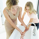 woman holding a girl's burnt hand under a tap of water
