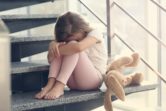 Sad little girl sitting in the staircase.