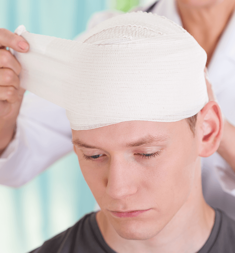 Photograph of head injury being wrapped in gauze